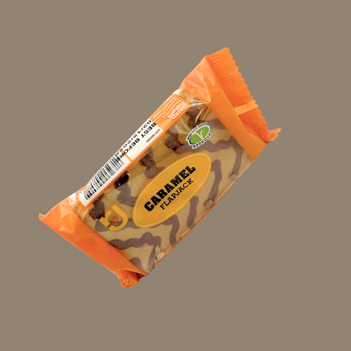 Hand holding a caramel snack bar against a picnic blanket backdrop