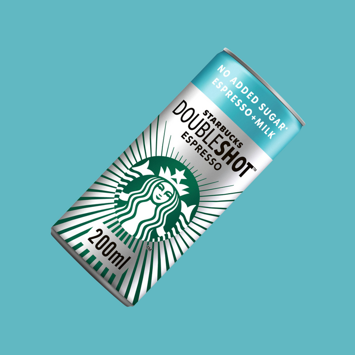 Hand holding a Starbucks DoubleShot Espresso can beside gym equipment, highlighting portable energy