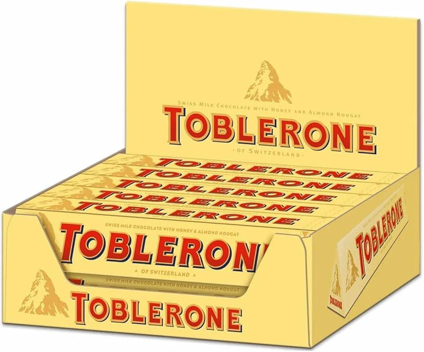 Close-up of Toblerone 10 x 100g pack displaying triangular chocolate peaks and Swiss mountain logo, milk chocolate with honey and almond nougat