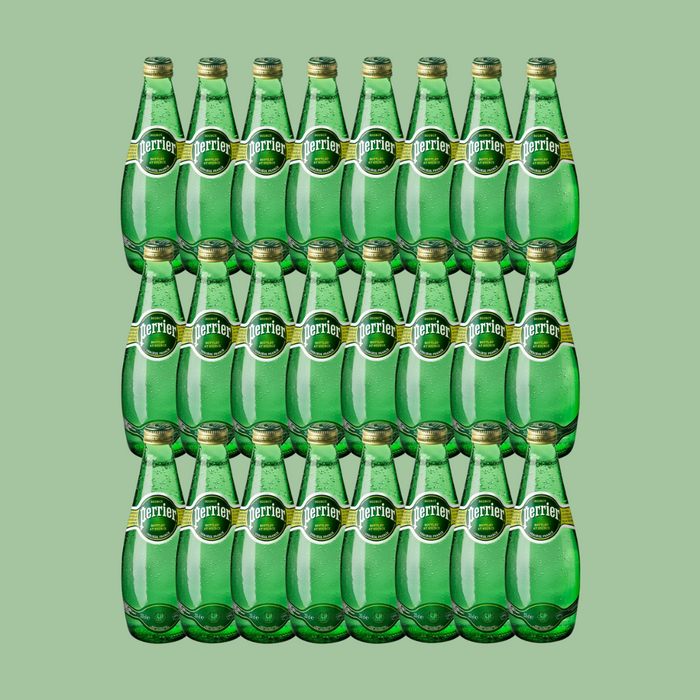 Open Perrier bottle pouring sparkling water into a glass over ice

